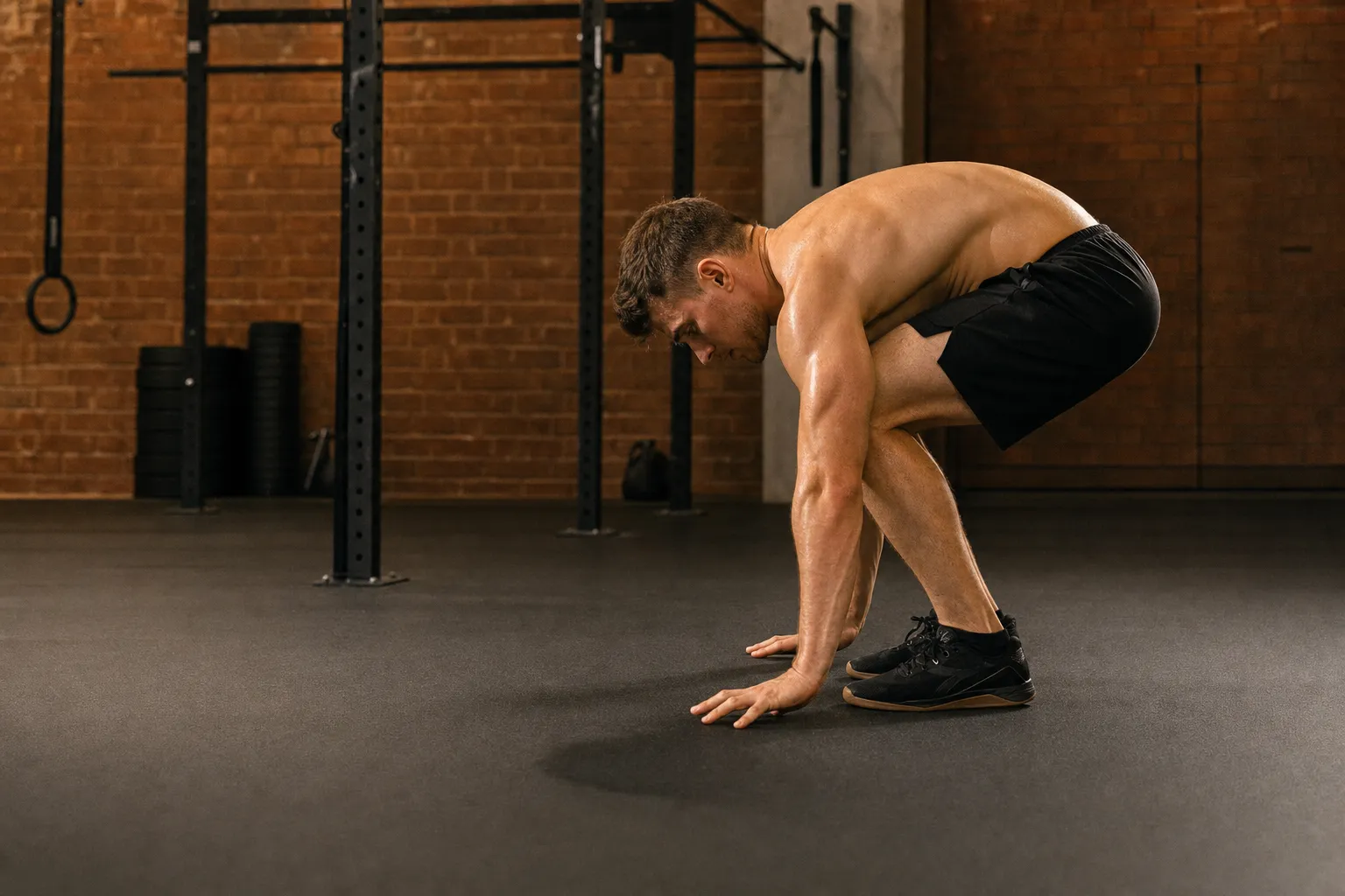 Athlete showing incorrect burpee form with rounded back during the squat phase and stiff-legged landing from the jump